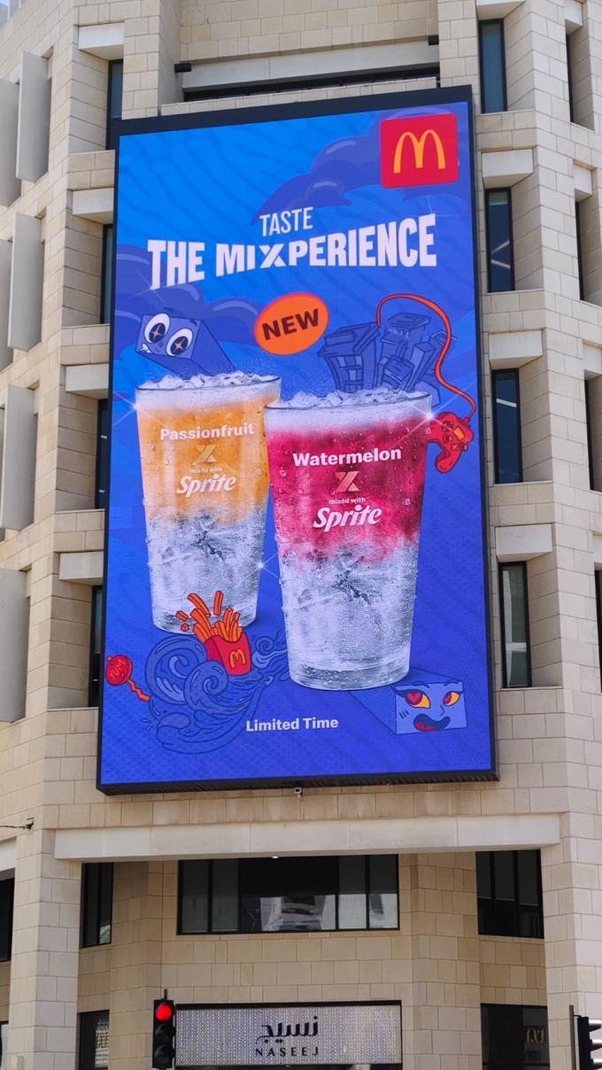 McDonald's Taste the Mixperience digital billboard in Doha showing Passionfruit and Watermelon Sprite drinks, recomposed from the same approved master as the Arabic version.